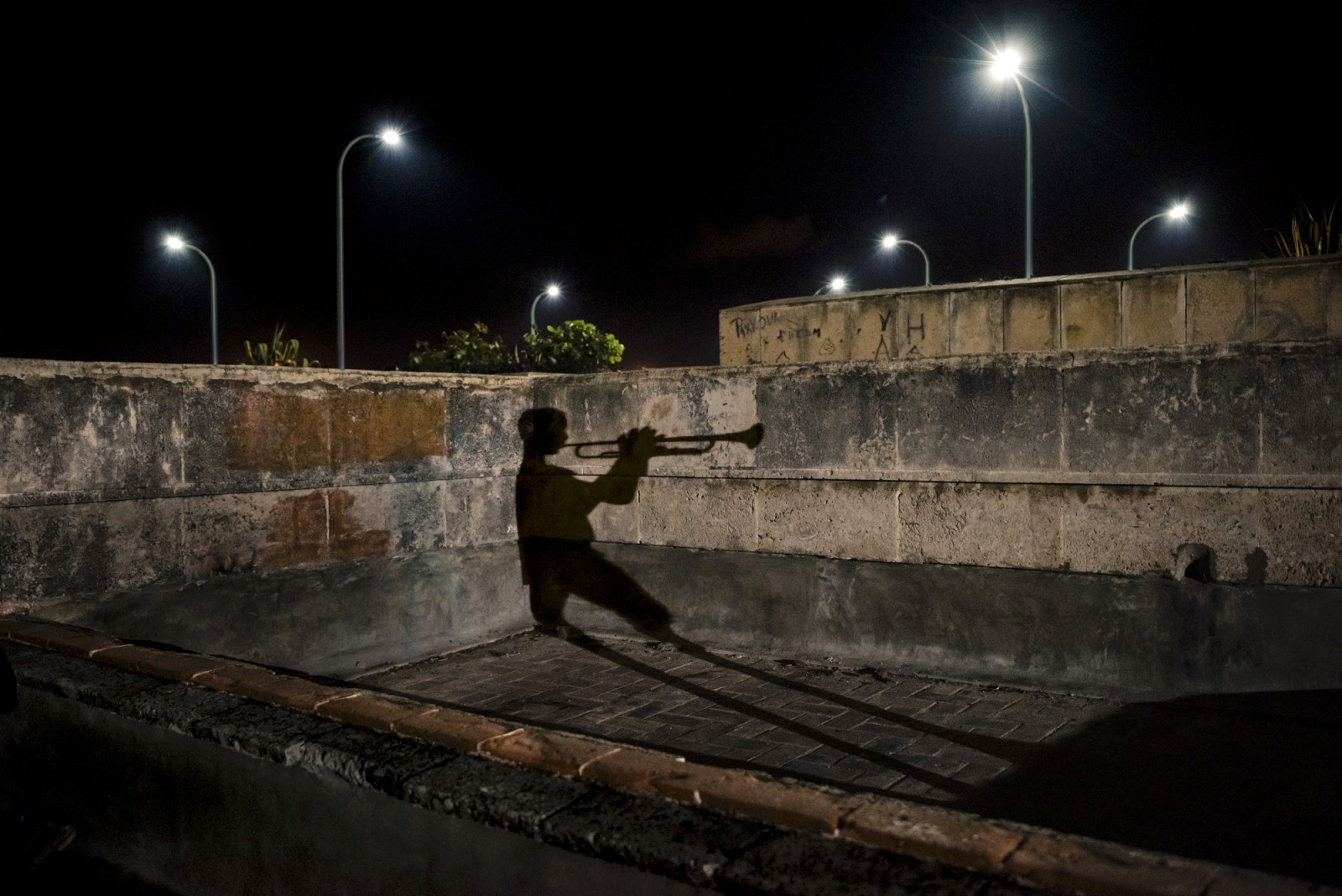 Havana, Cuba. December 2017. A 13-year-old boy, coming from Oriente province, is improvising old Cuban tunes on his trumpet on the roof of Hermanos Ameijeiras Hospital at night in central Havana. He said that most of the young people around him prefer reggaton these days and are not interested his kind of music and that makes him feel quite lonely.